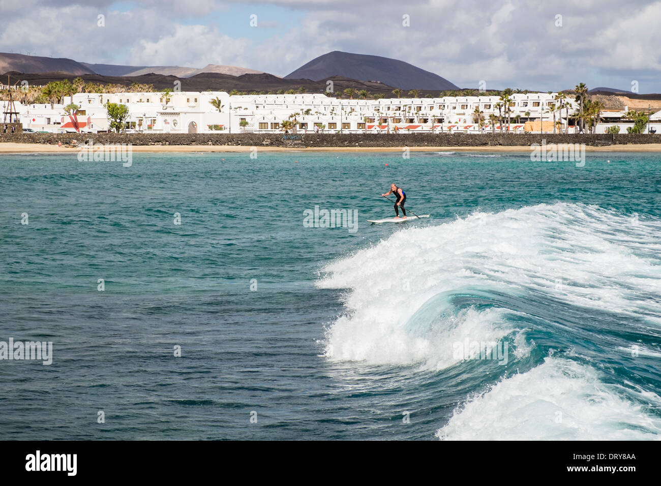 L'homme sur une planche de surf paddleboarding sur de grosses vagues en mer au large de Playa Charcos beach à Costa Teguise, Lanzarote, Îles Canaries Banque D'Images