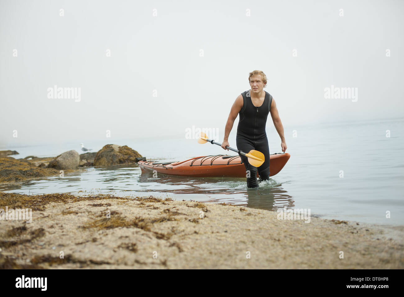 L'état de New York USA man wetsuit kayak sur le rivage en temps brumeux Banque D'Images