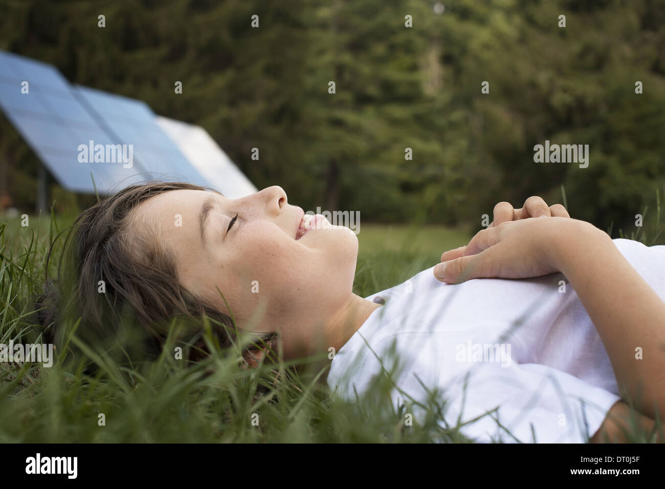Woodstock, New York USA garçon couché dans l'herbe à côté du panneau solaire Banque D'Images