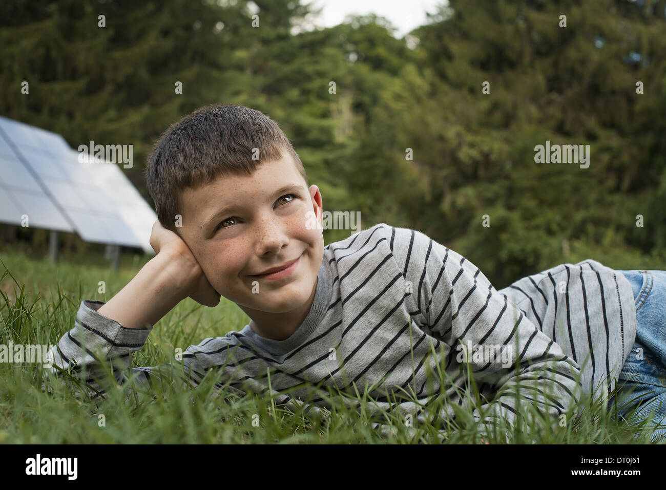 Woodstock, New York USA garçon couché dans l'herbe à côté des panneaux solaires Banque D'Images