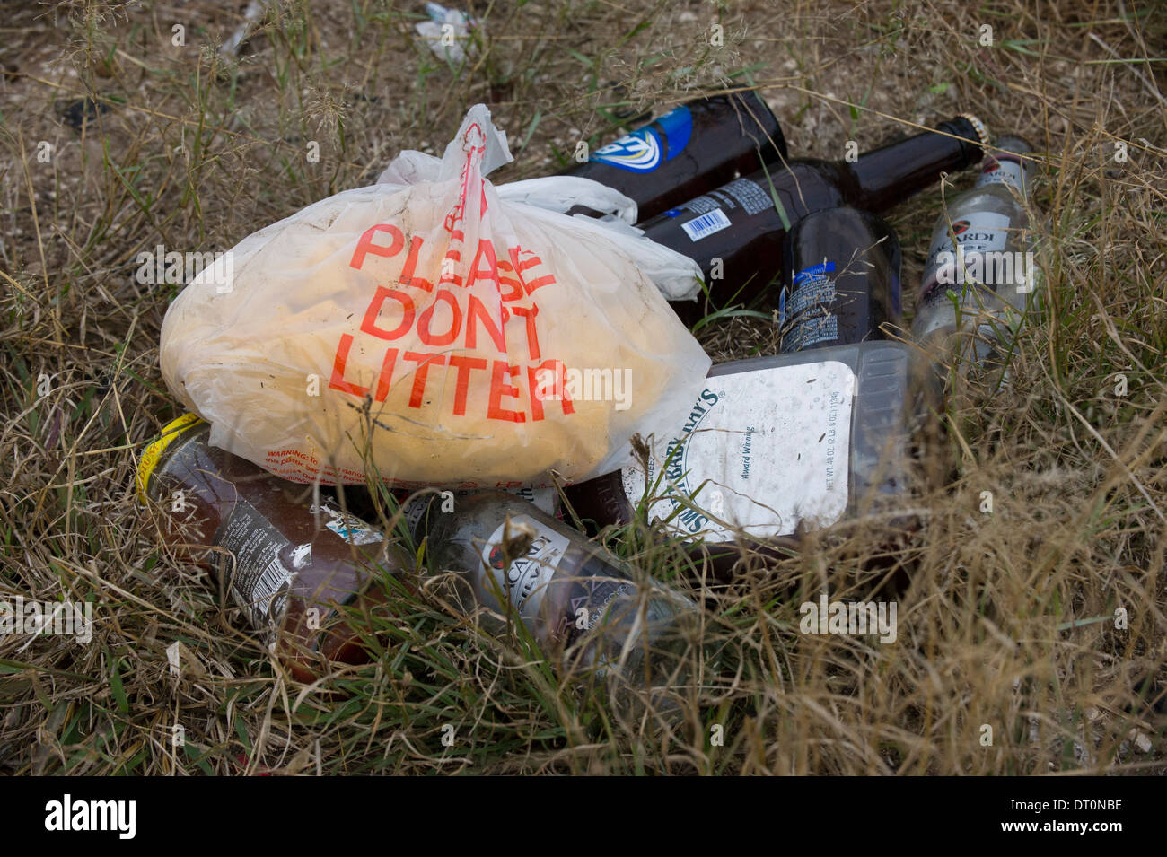 Les bouteilles en verre vides et autres déchets dans un 'n' pas de déchets le sac en plastique sur la masse à un arrêt de repos en milieu rural sud du Texas. Banque D'Images