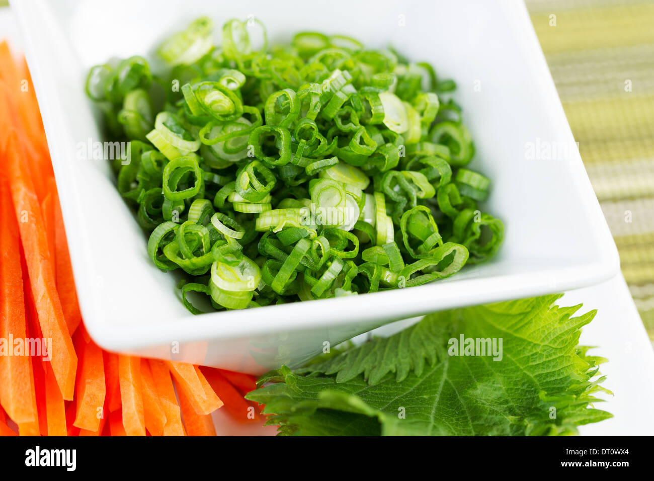 Libre de photo horizontale, oignons verts frais placés dans un bol blanc, et les tranches de carottes coupes utilisées comme ingrédients sushis Banque D'Images