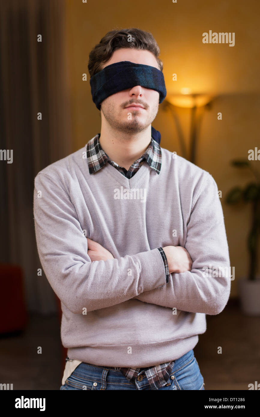 Jeune homme, les yeux bandés, à la maison dans la salle de séjour ne peuvent pas voir Banque D'Images