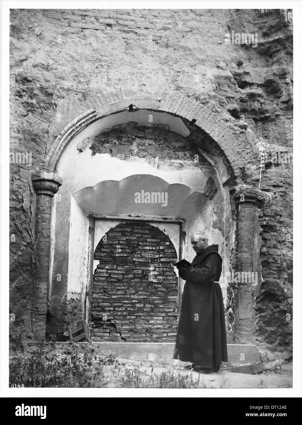 Le Père supérieur O'Keefe se tient debout devant une porte murée de la Mission San Luis Rey de Francia en Californie, capturée en 1904, présentant l'architecture historique de la mission. Banque D'Images