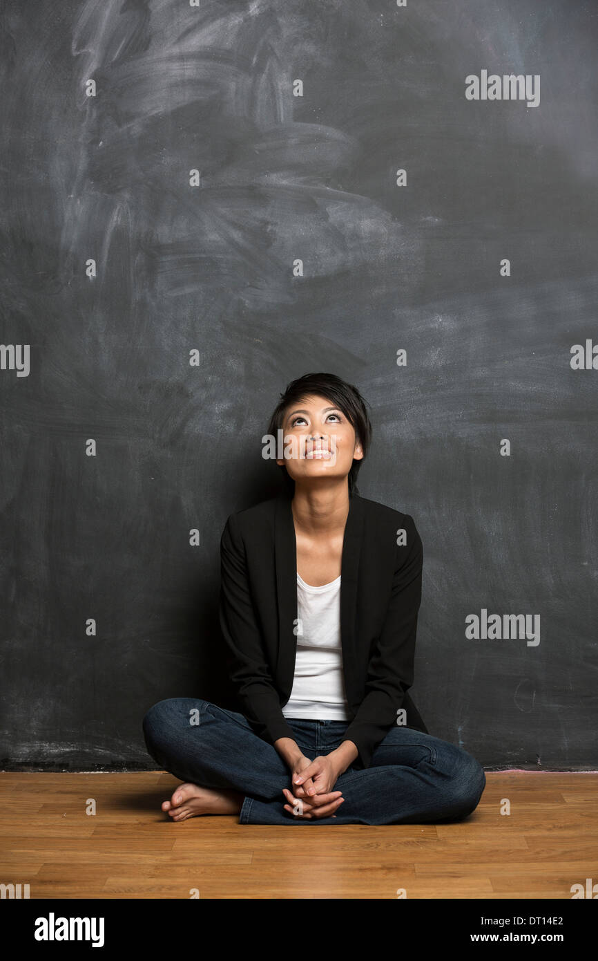 Happy Asian femme assise en face d'un tableau. Banque D'Images