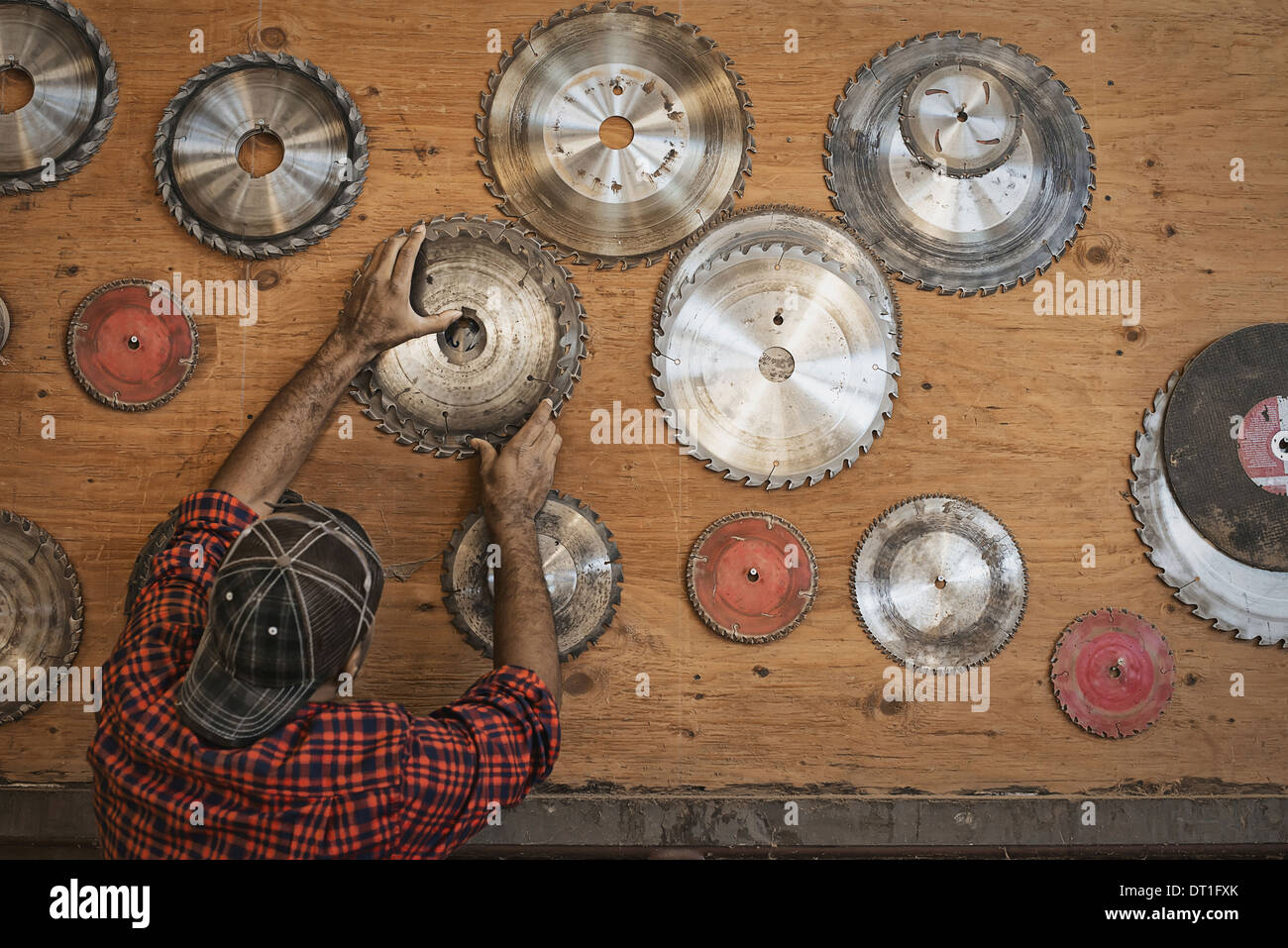 Un atelier de bois d'un homme régénéré atteignant jusqu'à un conseil de stockage pour lames de scie circulaire pour remplacer une lame Banque D'Images
