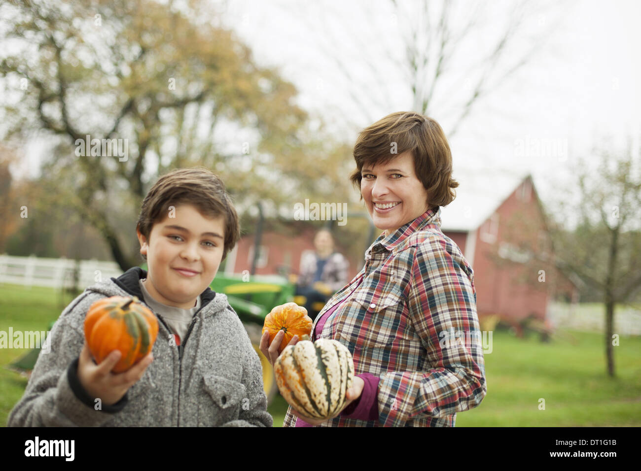 Deux personnes, une femme et un enfant dans une ferme bio transportant des légumes récoltés courges et citrouilles l'agriculture biologique Banque D'Images