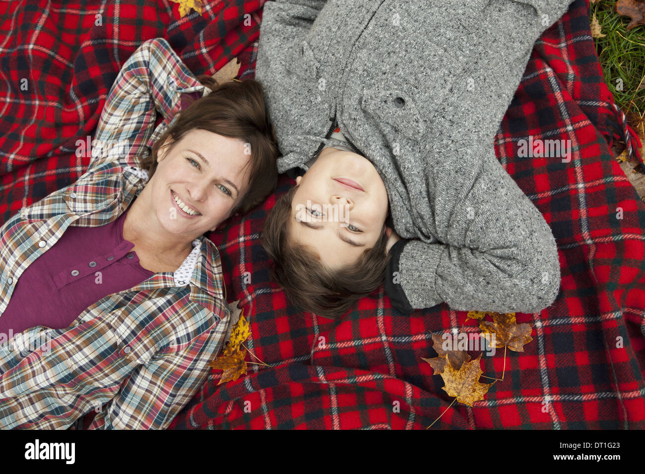 Deux personnes, une femme et un enfant allongé sur une couverture de pique-nique tartan rouge regardant vers le haut Banque D'Images