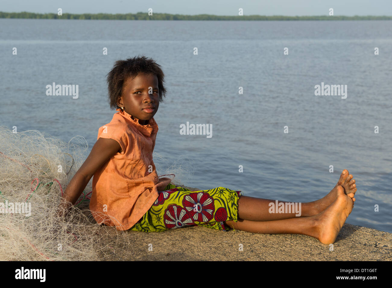 Fille assise sur un filet de pêche sur la jetée du village, la Gambie  Tendaba Photo Stock - Alamy