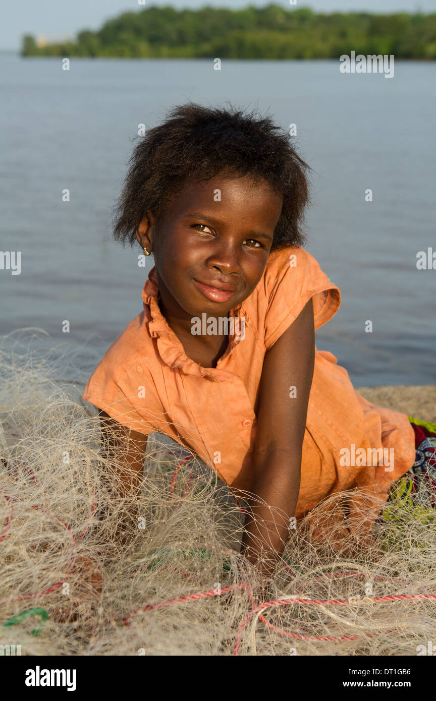 Fille assise sur un filet de pêche sur la jetée du village, la Gambie  Tendaba Photo Stock - Alamy