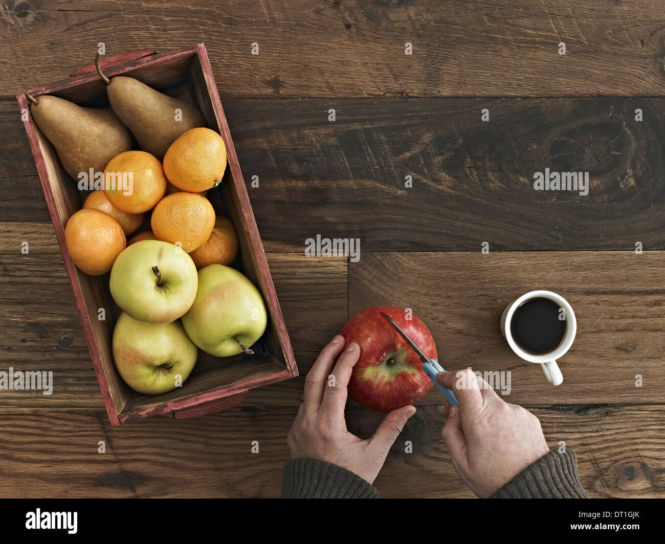 Une table en bois haut de gamme d'un bois fort de fruits frais les poires et les oranges une personne coupant une pomme Banque D'Images