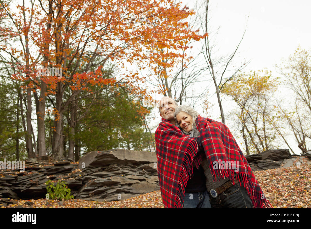 Un couple homme et femme sur une journée à l'automne le partage d'un tapis de pique-nique pour garder au chaud Banque D'Images