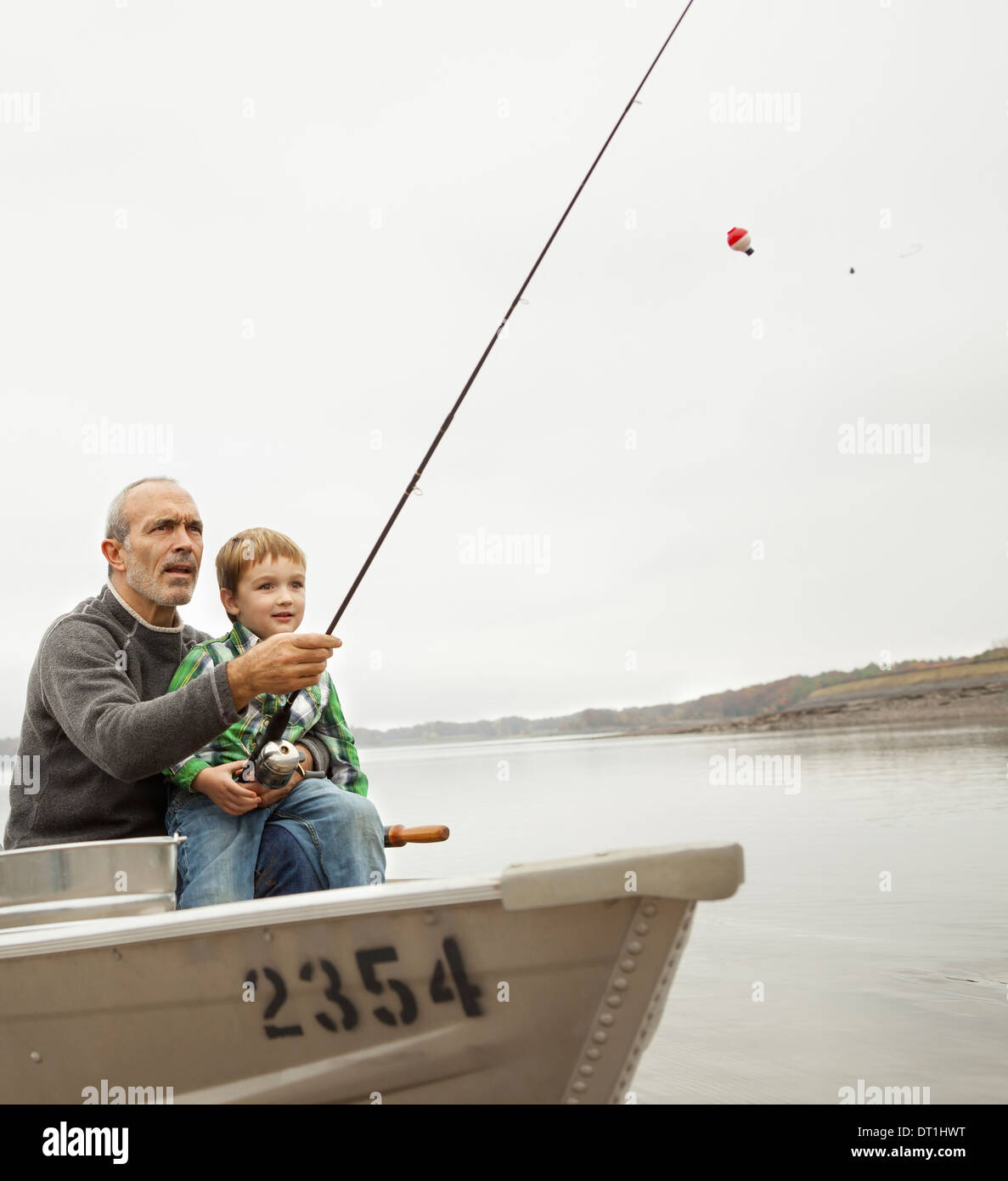 Une journée au lac Ashokan approvisionne un homme montrant un jeune garçon comment pêcher assis dans un bateau Banque D'Images