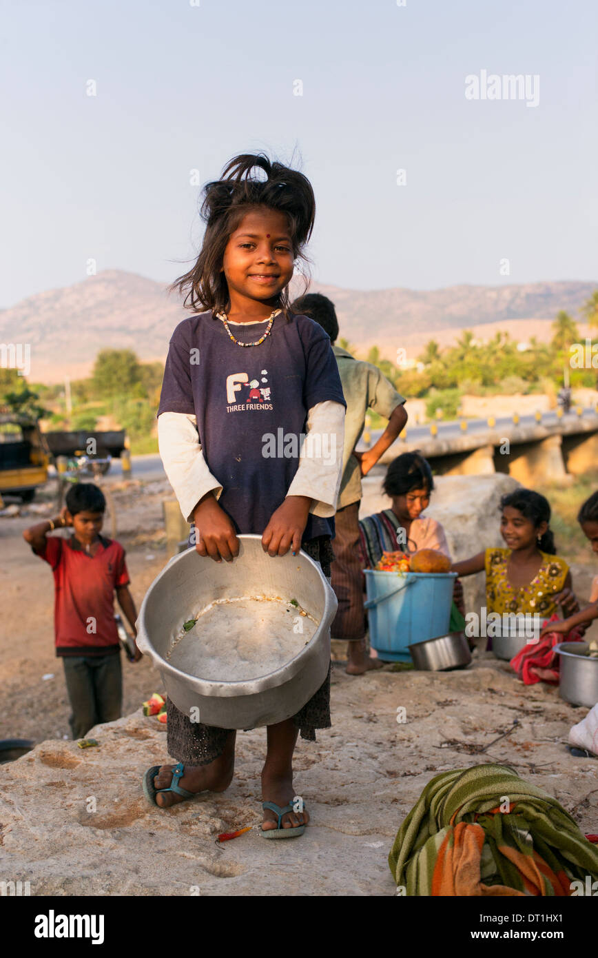 Heureux les pauvres basse caste indienne debout sur un rocher tenant une casserole à un marché indien. L'Andhra Pradesh, Inde Banque D'Images