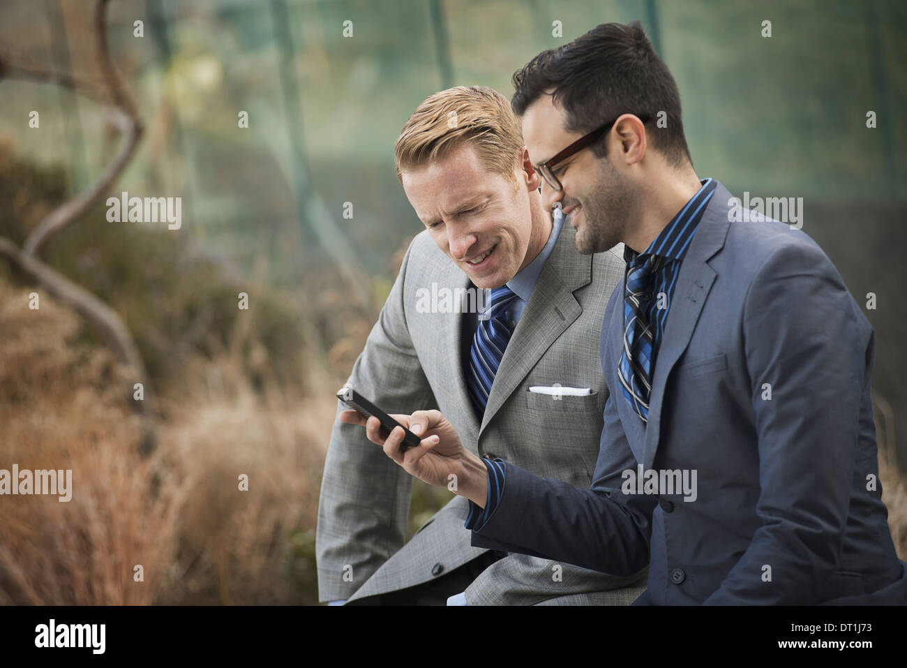 Deux hommes en vêtements d'affaires officiel côte à côte en regardant un écran de téléphone cellulaire ou un téléphone mobile Banque D'Images
