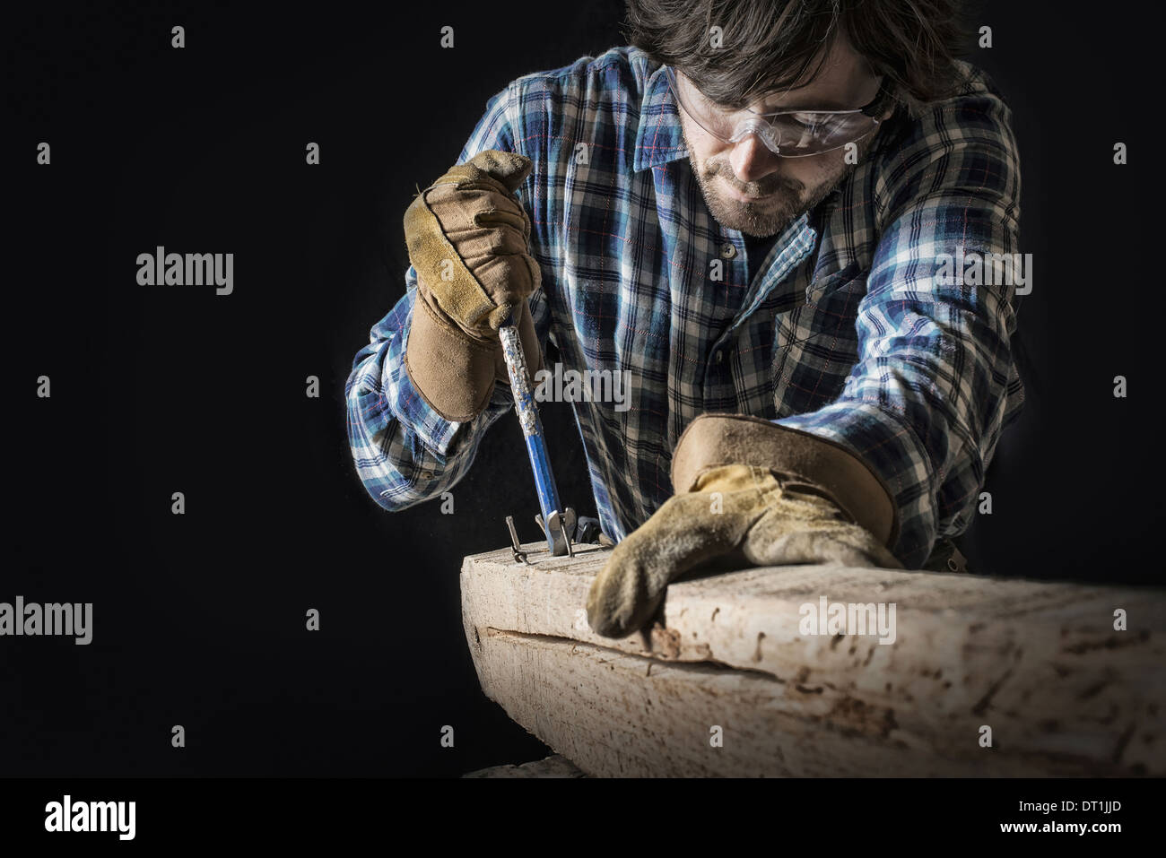 Un homme travaillant dans un chantier de bois récupérés et outils de maintien de l'atelier de l'extraction des ongles d'une inégale et noués, morceau de bois Banque D'Images
