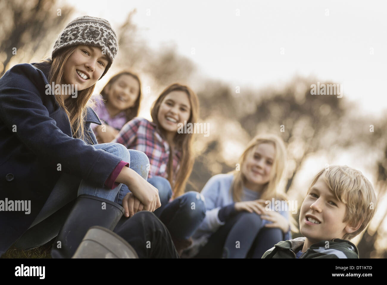 Cinq enfants dans une ferme, garçons et filles dans des manteaux chauds en plein air Banque D'Images