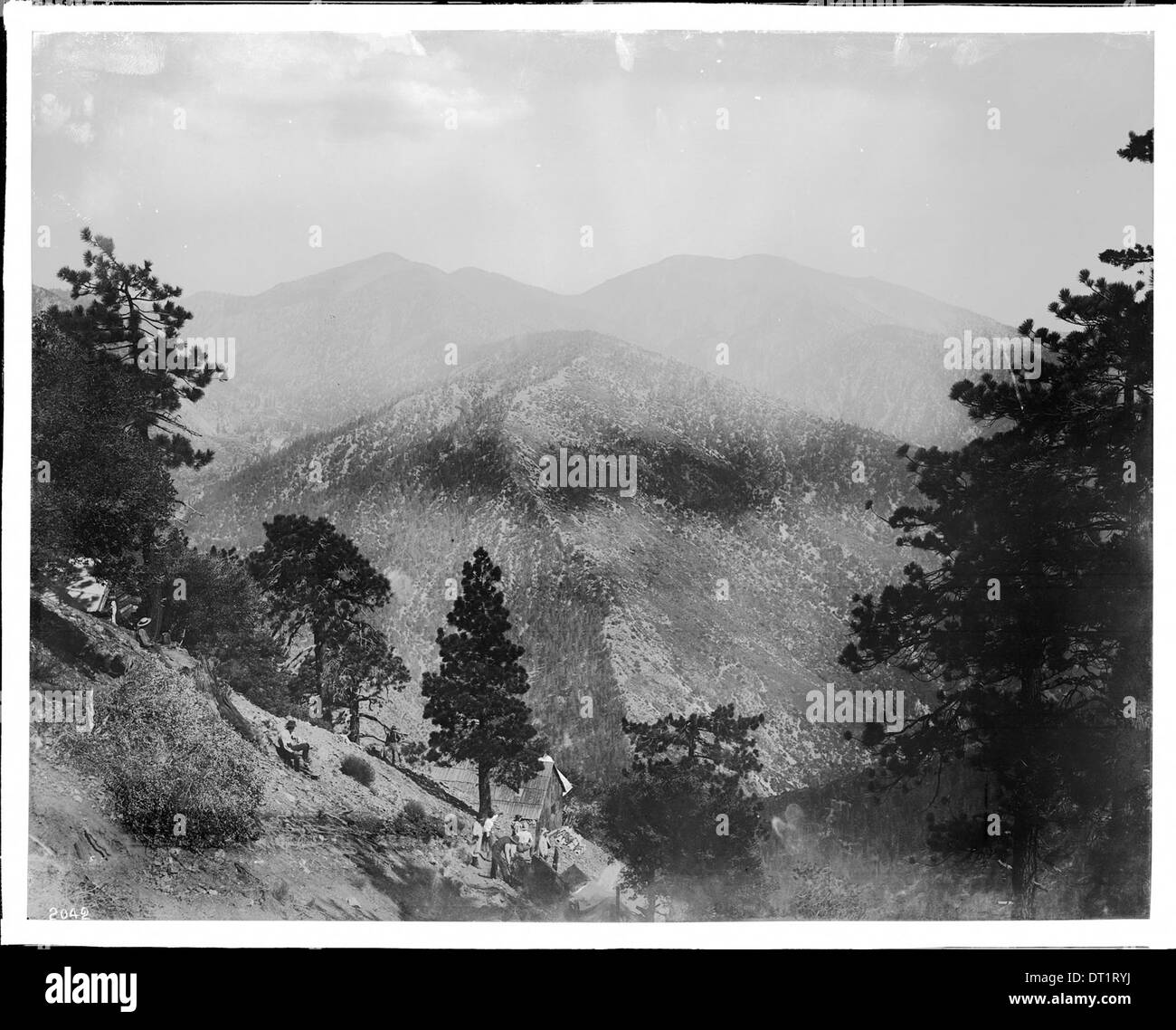 Photographie d'un groupe de personnes rassemblées sur une pente de montagne près d'un bâtiment, avec le mont San Antonio en arrière-plan, prise vers 1900. Banque D'Images