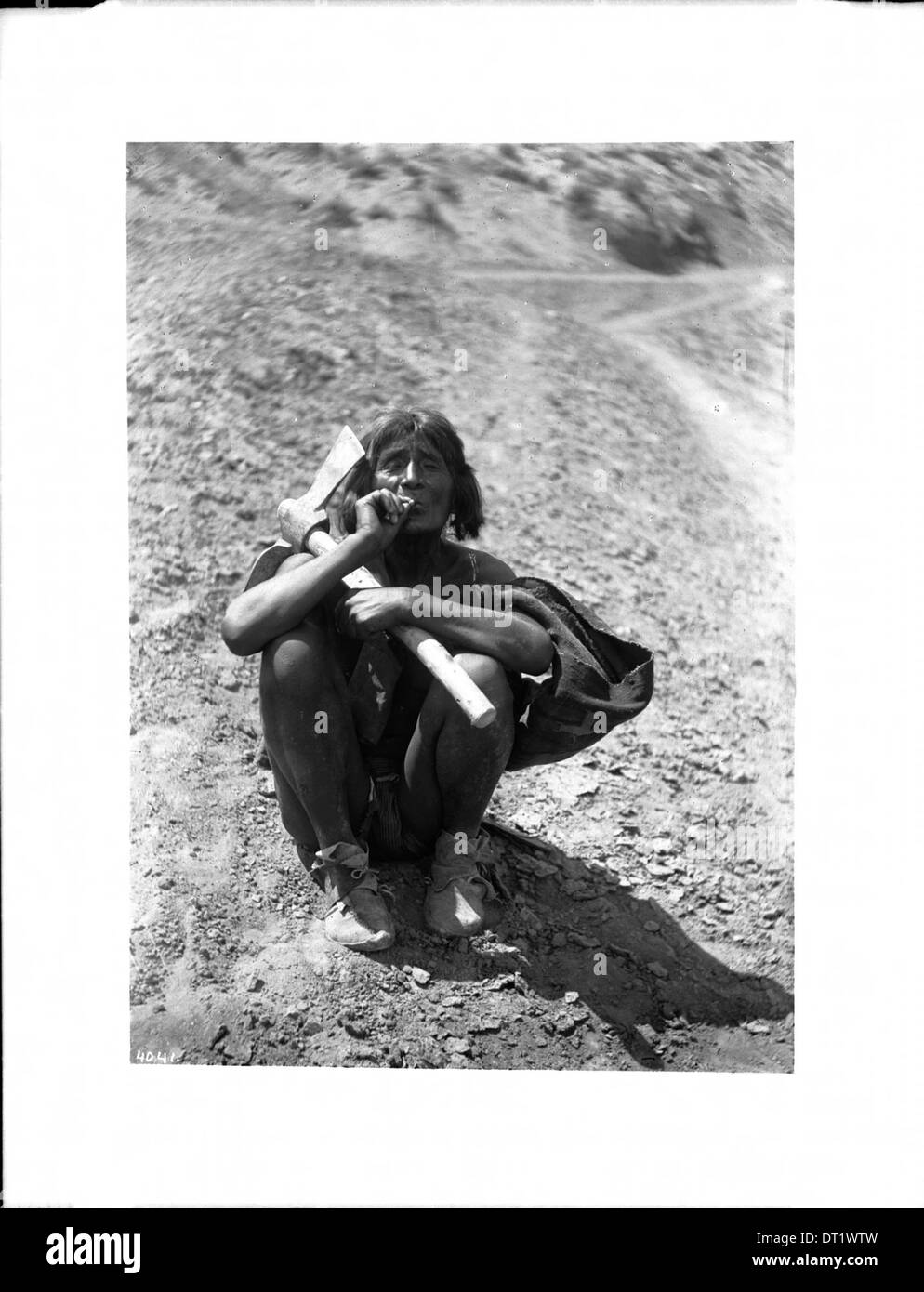 Un fermier indien Hopi est capturé en train de se détendre tout en fumant une cigarette. La photographie reflète un moment de calme dans son quotidien vers 1900. Banque D'Images