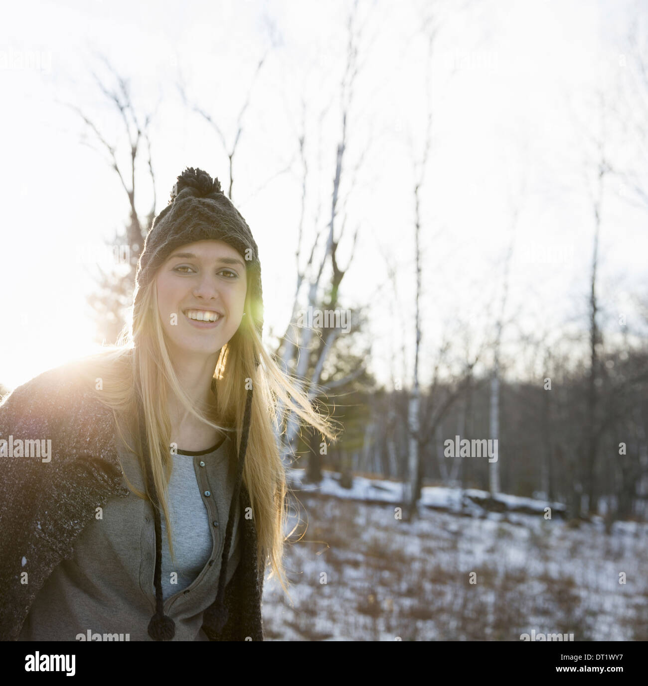 Une jeune femme avec des cheveux blonds et un bonnet de laine tricoté et enduire l'extérieur, un jour d'hiver neige au sol Banque D'Images