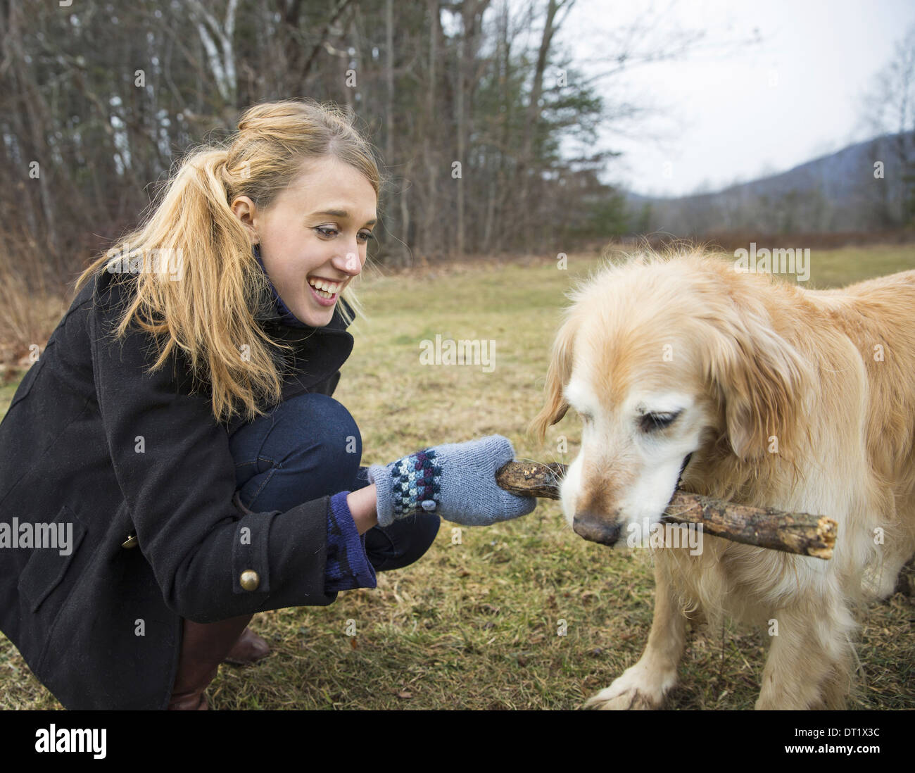 Une jeune femme à l'extérieur l'hiver sur une marche avec un golden retriever dog Banque D'Images