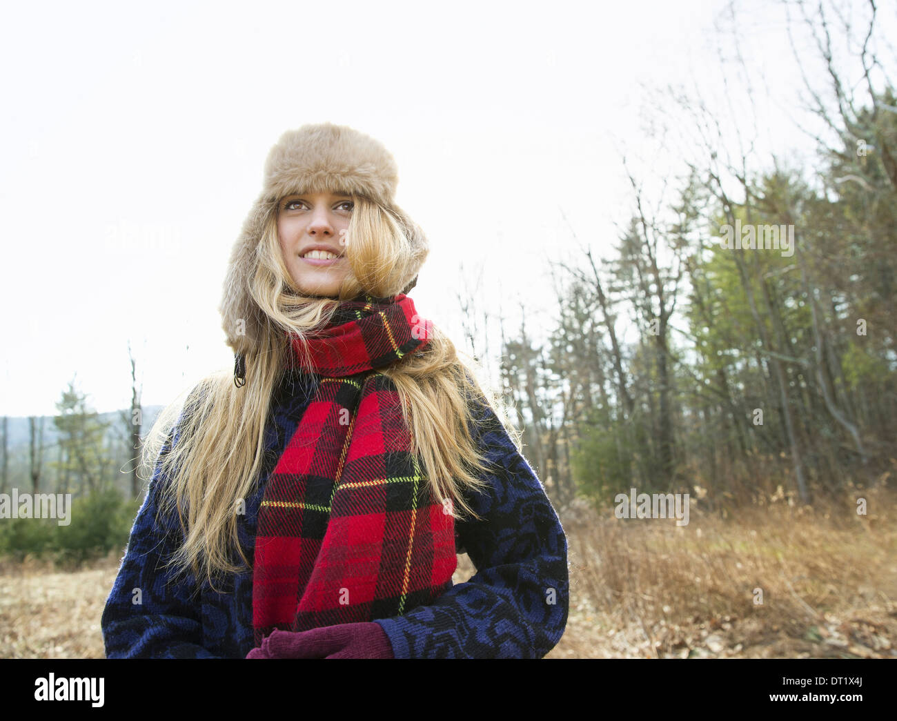 Une femme dans une ambiance chaleureuse et un grand chapeau de fourrure Écharpe de tartan rouge à l'extérieur en hiver Banque D'Images