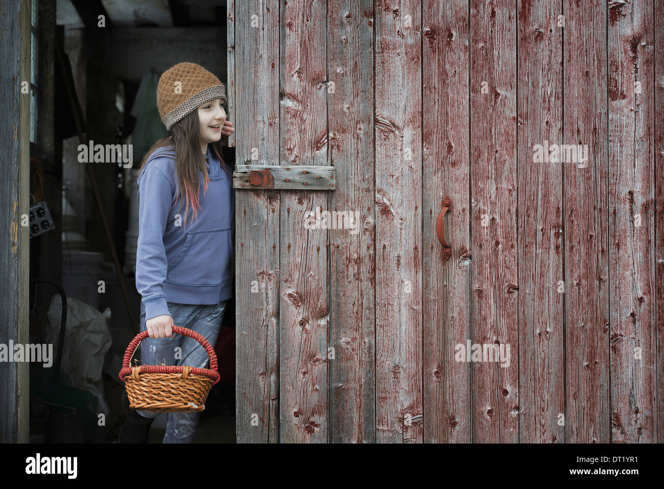 Une ferme biologique dans le nord de New York en hiver, une fille dans une grange de la porte avec un panier Banque D'Images
