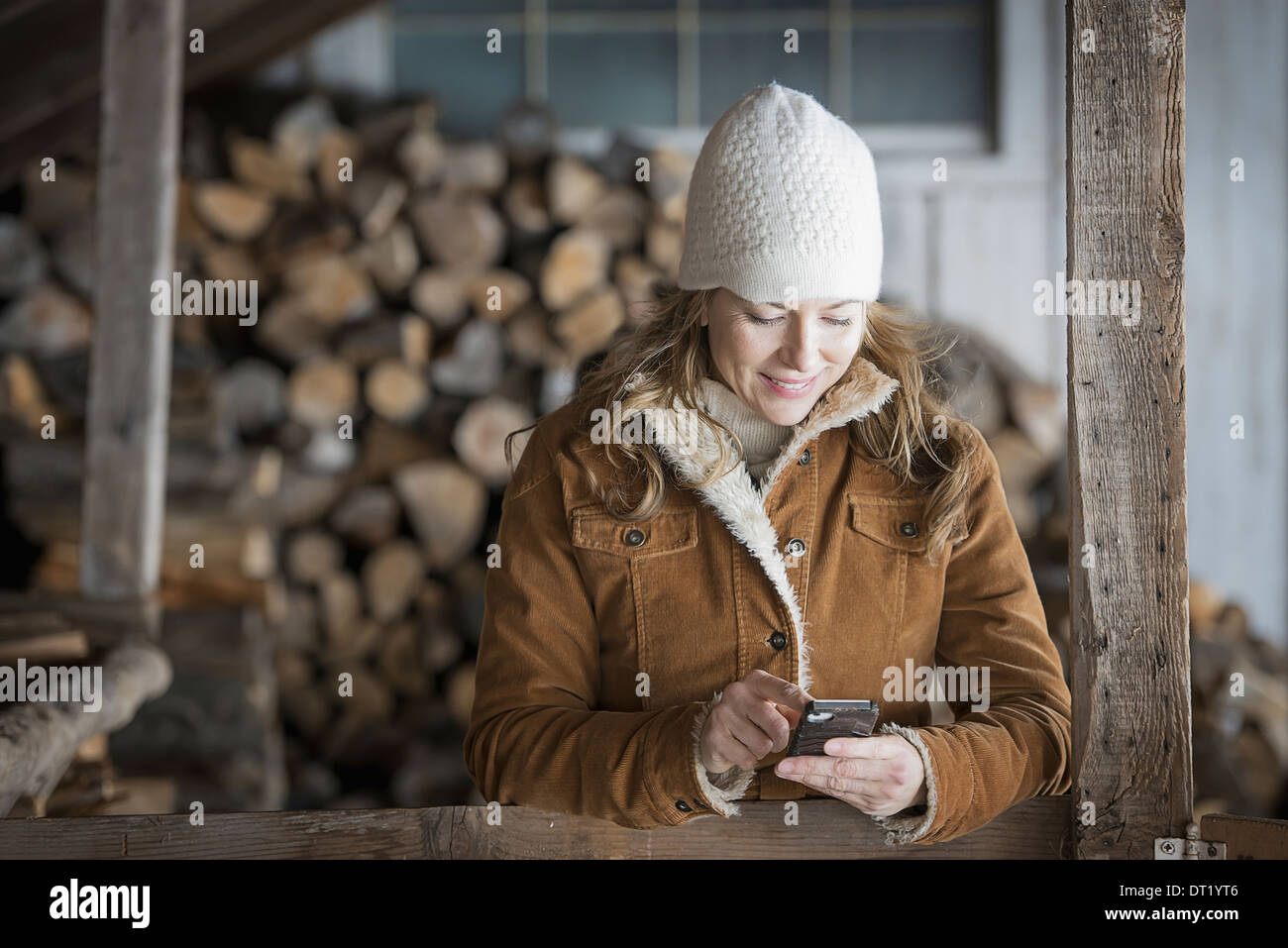 Une ferme biologique dans le nord de New York en hiver une femme en manteau de laine de mouton et de hat en utilisant un téléphone cellulaire Banque D'Images