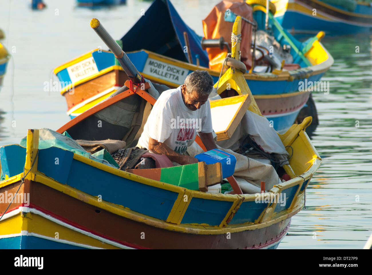 Pêcheur maltais au travail dans son luzzu ou bateau traditionnel dans le port de Marsaxlokk Banque D'Images