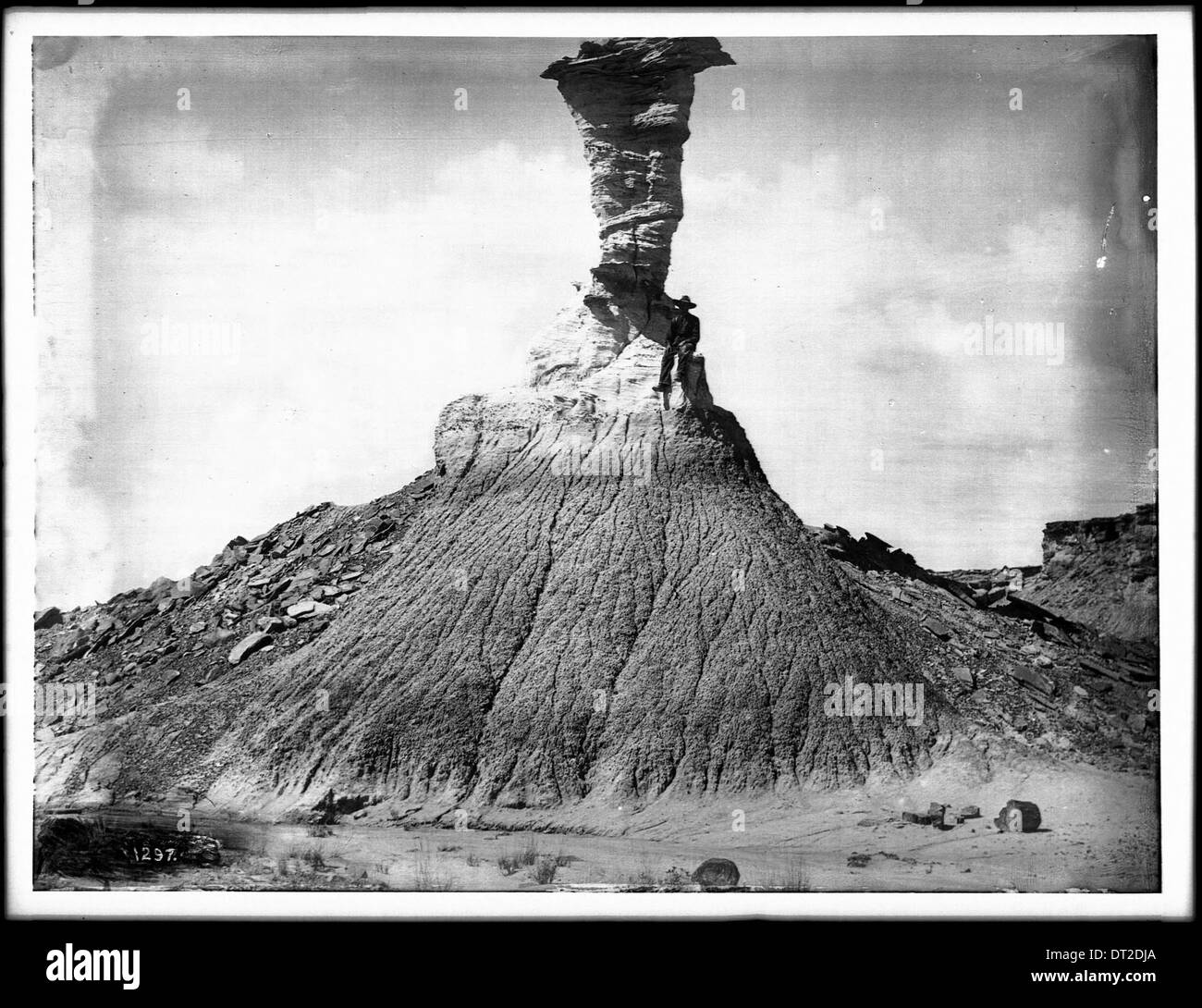 Un homme assis sur une formation rocheuse appelée Eagle Head dans la forêt pétrifiée de l'Arizona, capturé vers 1900, montrant le paysage désertique et les caractéristiques géologiques. Banque D'Images