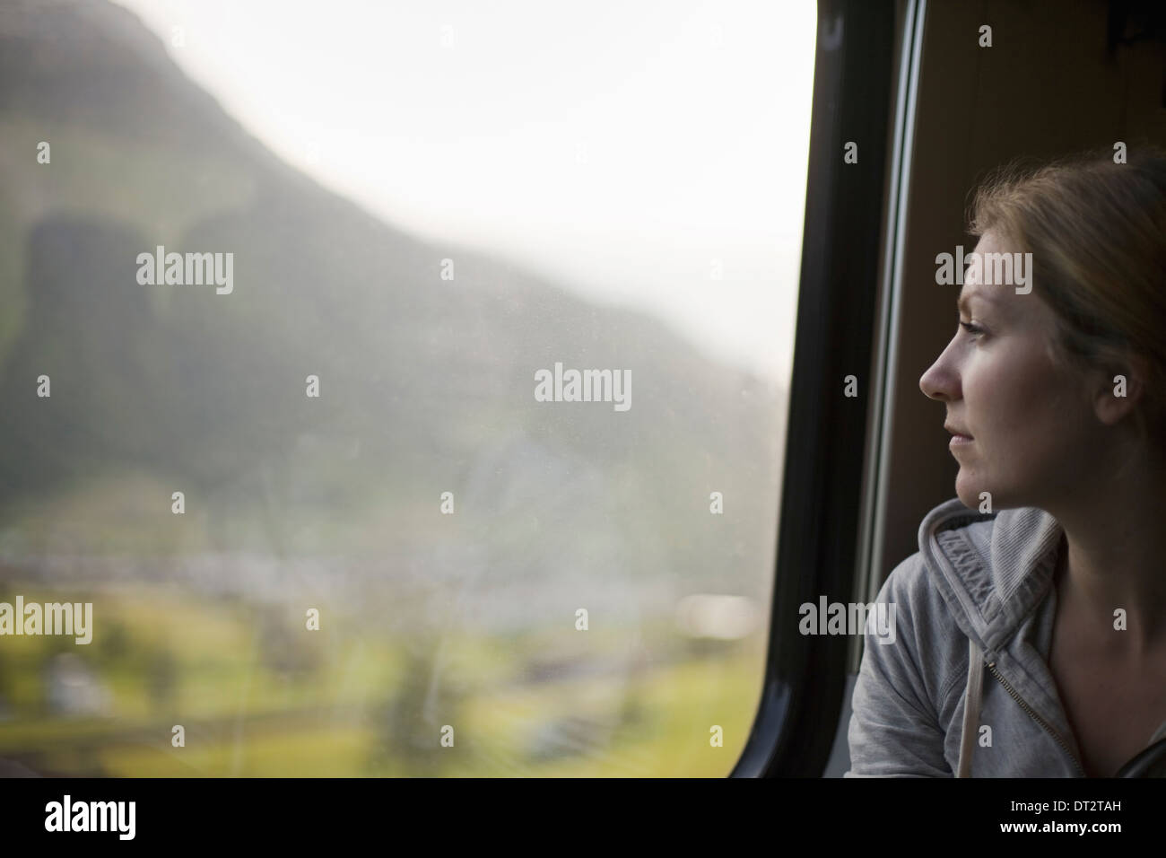 Une femme assise par un train fenêtre donnant sur le paysage Banque D'Images