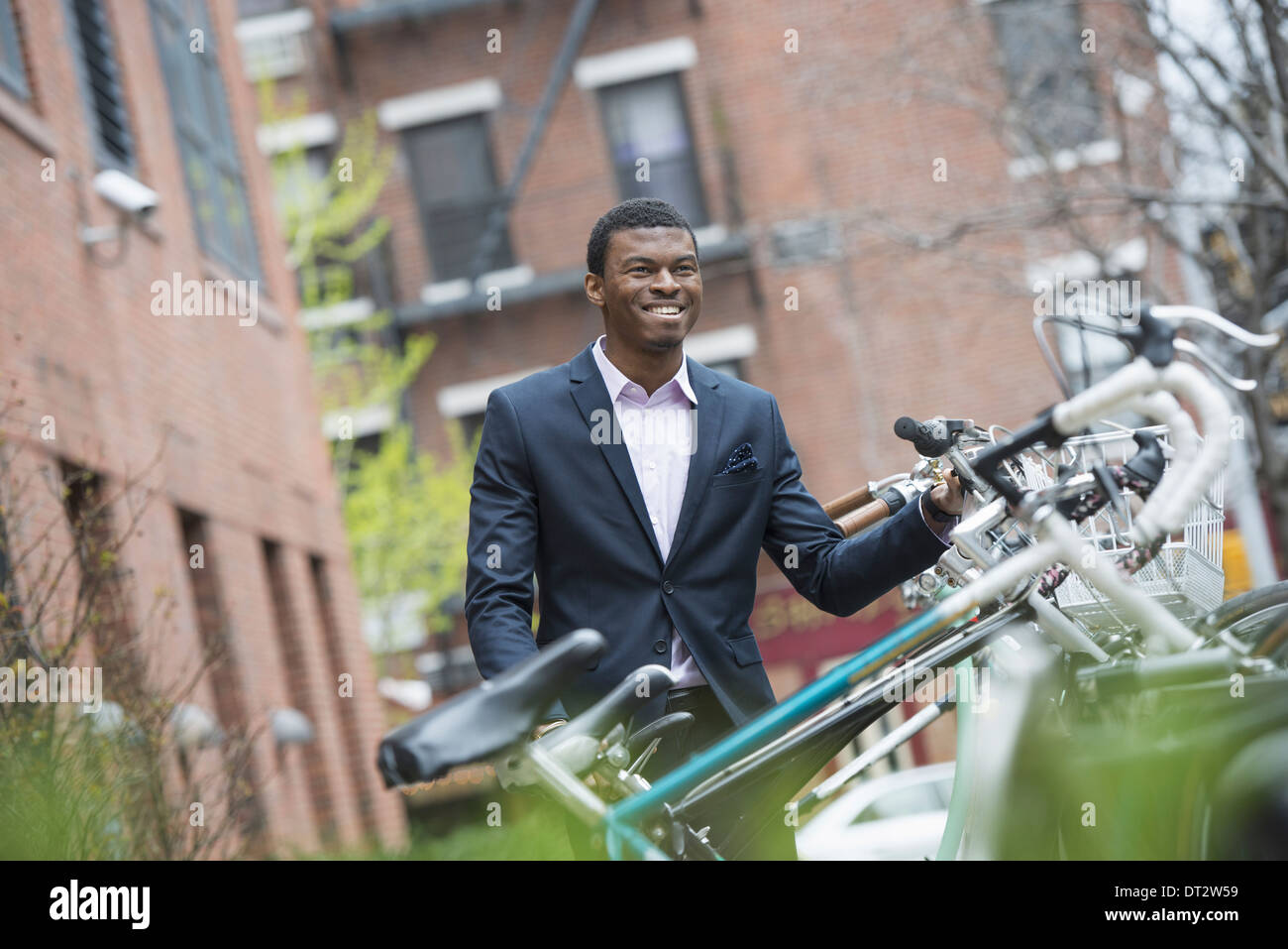 Vue sur cityA homme dans un costume bleu par un support à bicyclettes dans un parc de la ville Banque D'Images