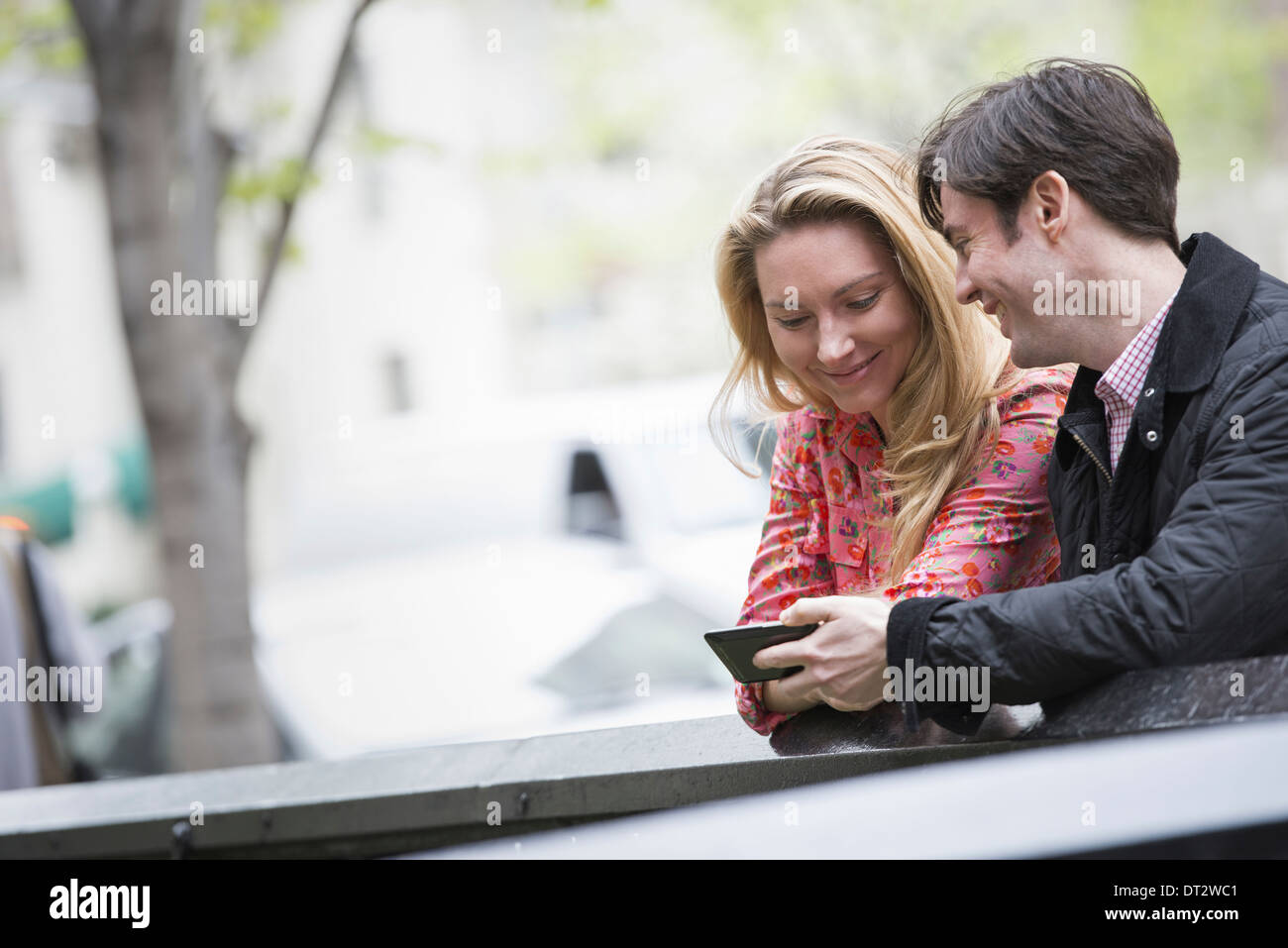 Vue sur cityYoung les gens à l'extérieur dans un parc de la ville deux personnes assises côte à côte en regardant un téléphone intelligent Banque D'Images