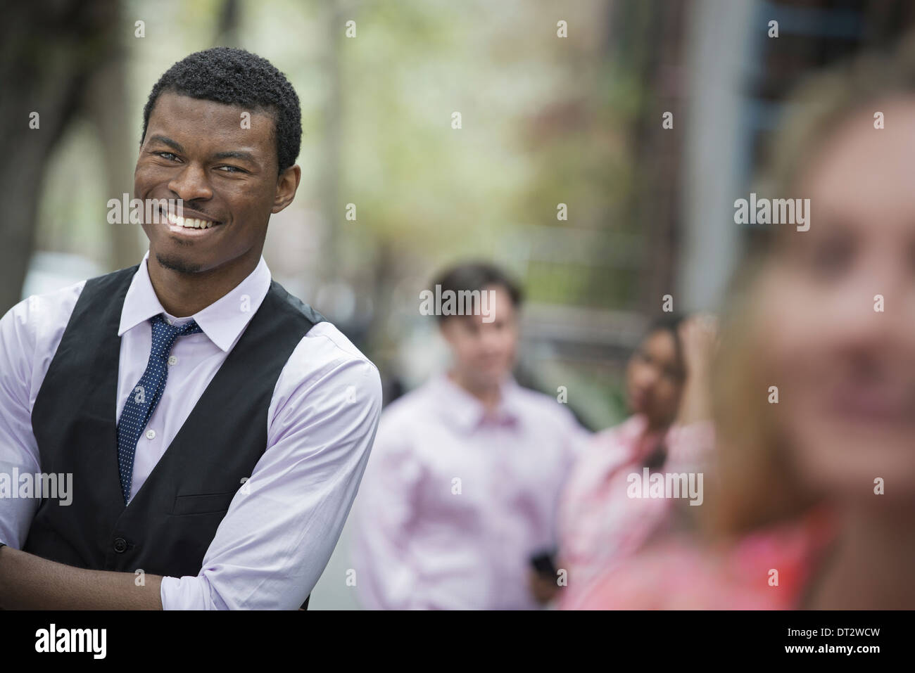 Vue sur cityYoung les gens à l'extérieur dans le parc de la ville un homme les bras croisés de sourire et de trois autres personnes regroupées autour de lui Banque D'Images