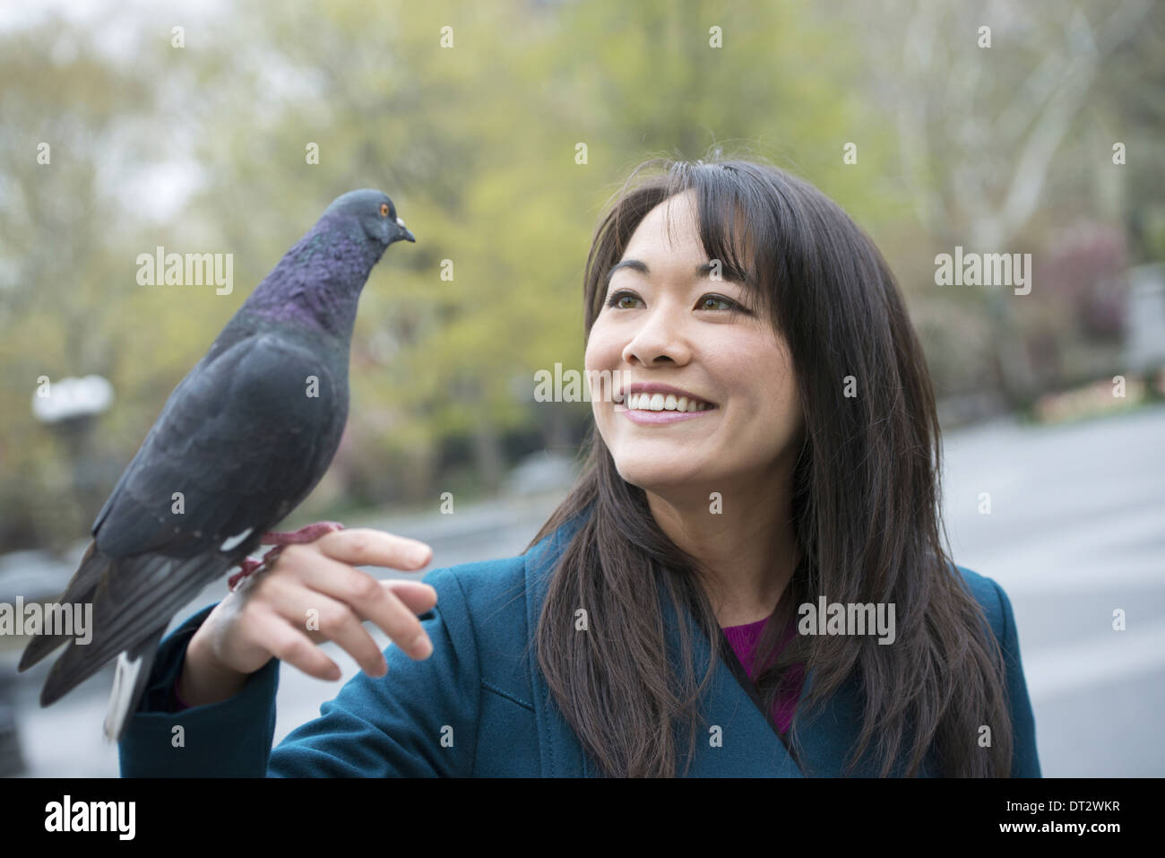 Une jeune femme dans le parc avec un pigeon perché sur son poignet Banque D'Images