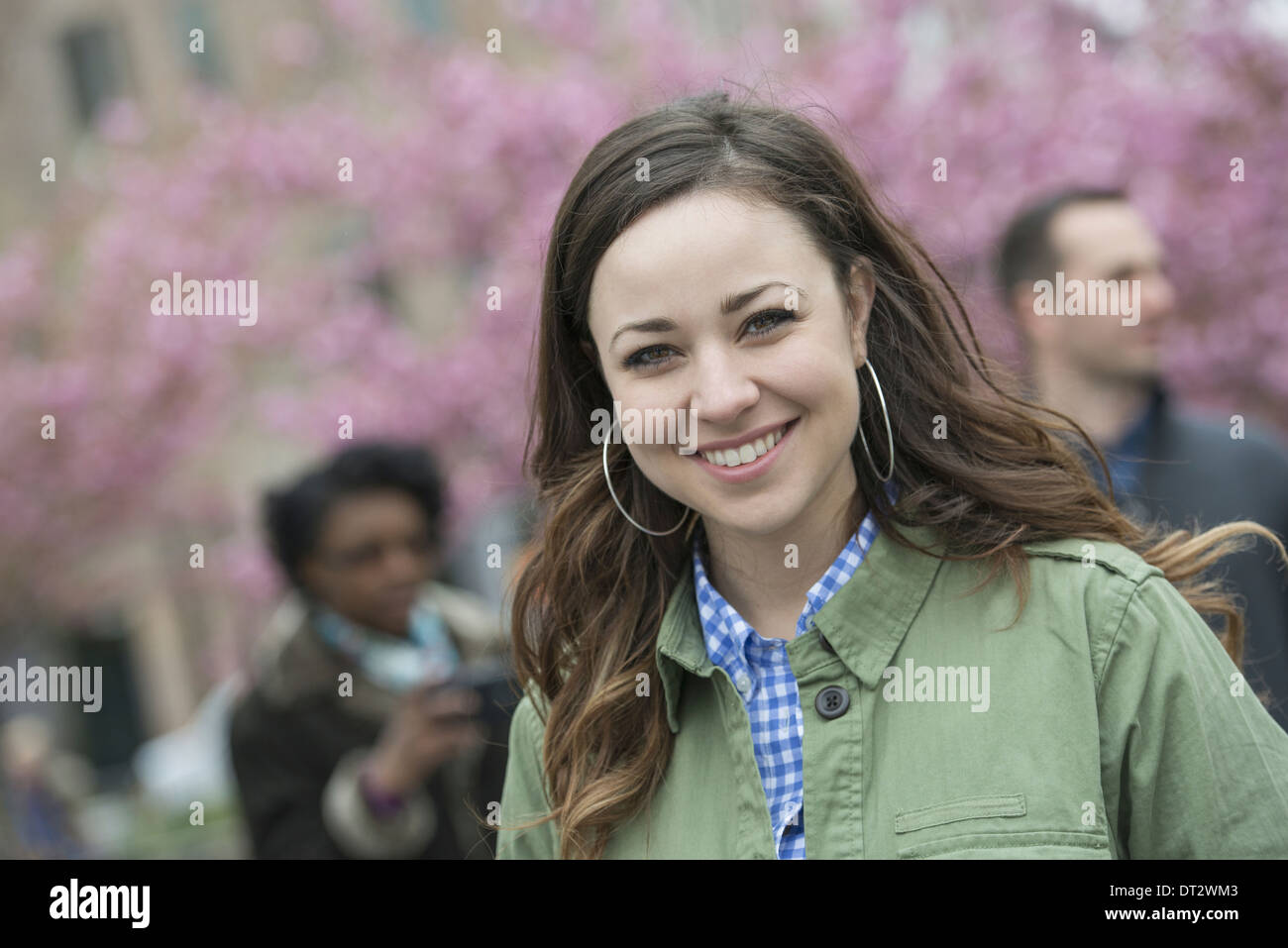 Cerisiers dans le parc une jeune femme en chemise à col ouvert souriant et regardant la caméra Banque D'Images