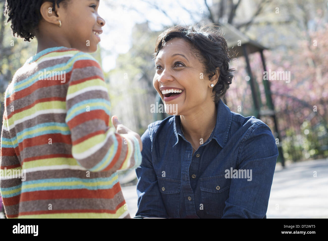 Soleil et cherry blossom une mère à genoux souriant à son fils Banque D'Images