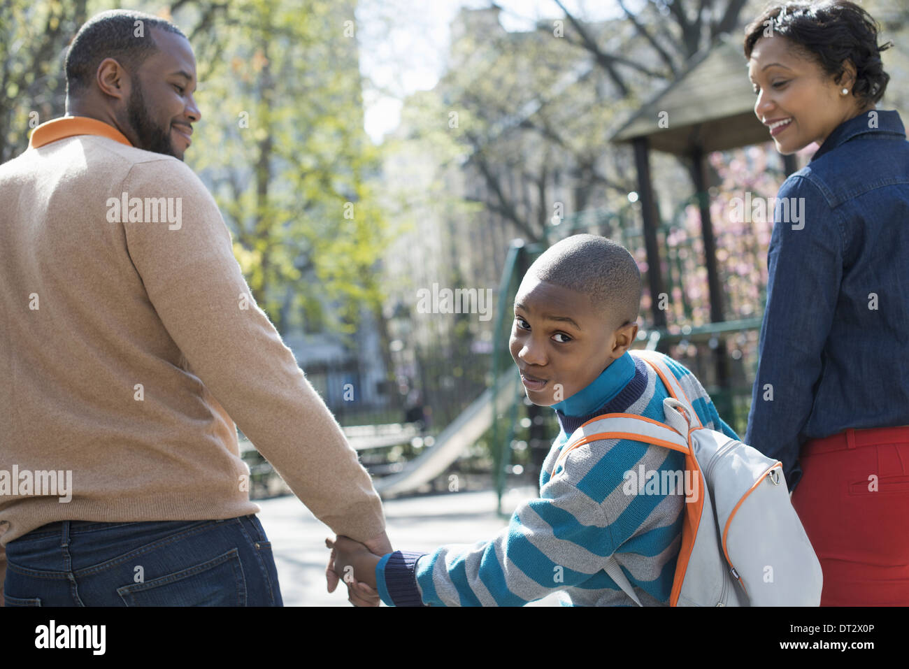 Soleil et fleur de cerisier Un garçon regardant par-dessus son épaule entre ses parents Banque D'Images