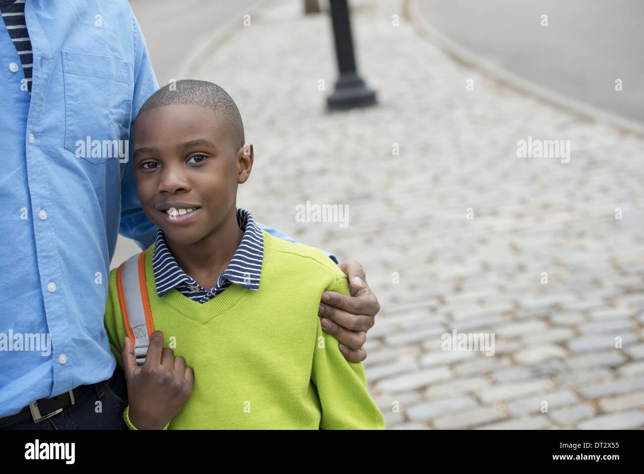 Un garçon tenant un sac à côté de son père Banque D'Images