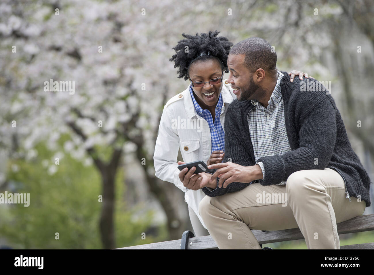 Un couple assis sur un banc, l'un tenant une Banque D'Images