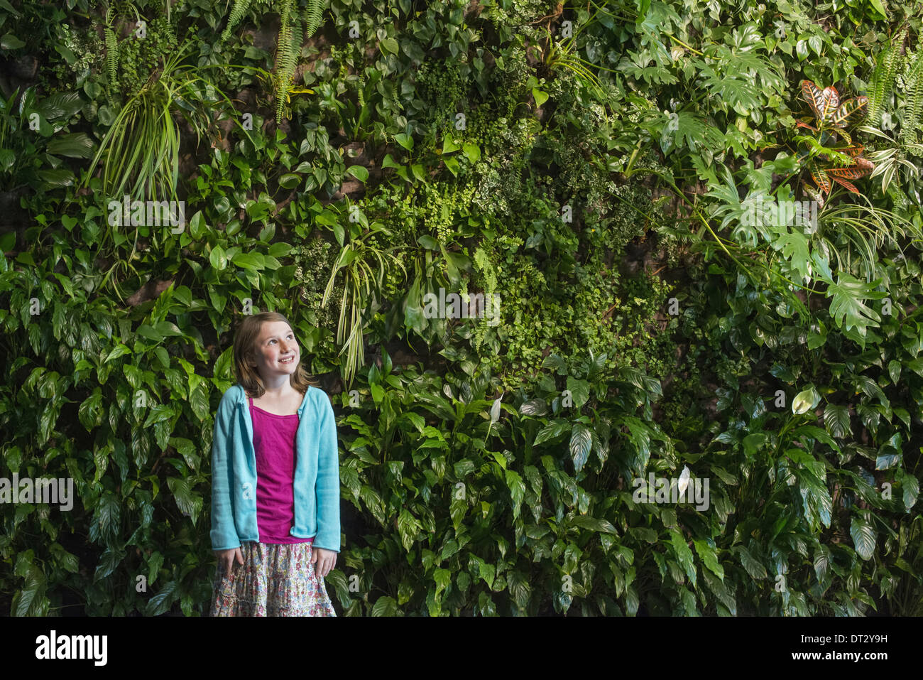 Ville au printemps un mode de vie urbain une jeune fille debout devant un mur recouvert de fougères et plantes grimpantes Banque D'Images