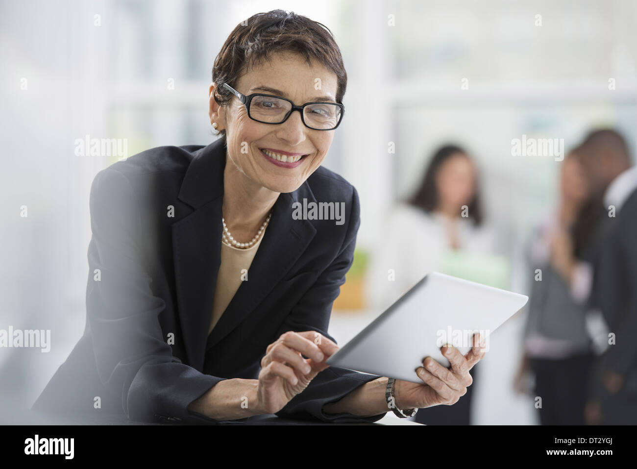 Une femme d'intérieur d'un bureau dans une veste noire à l'aide d'une tablette numérique Banque D'Images Une femme d'intérieur d'un bureau dans une veste noire à l'aide d'une tablette numérique Banque D'Images