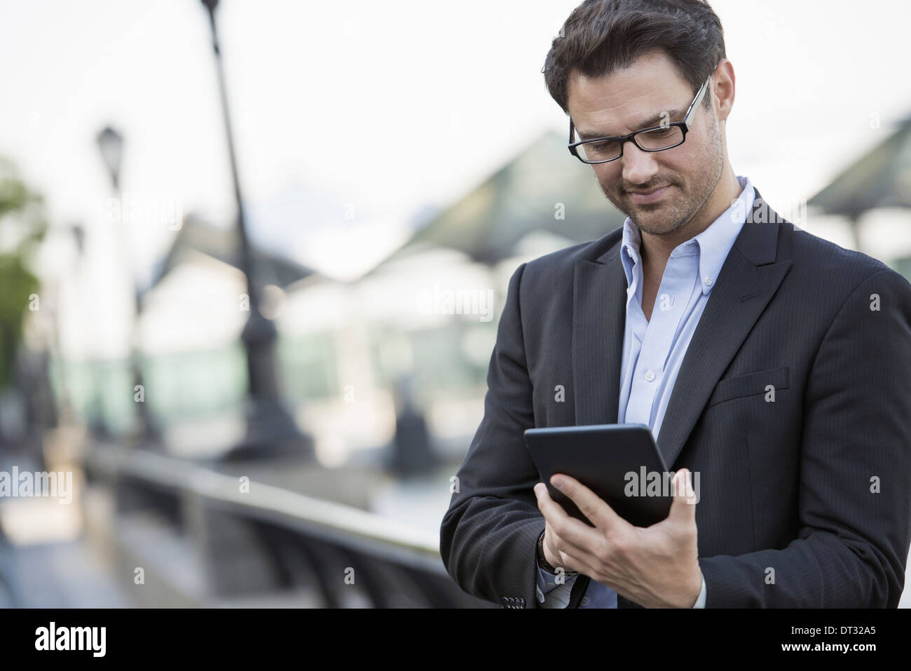 Les gens d'affaires à l'extérieur dans la ville de rester en contact en déplacement un homme debout tenant une tablette numérique Banque D'Images