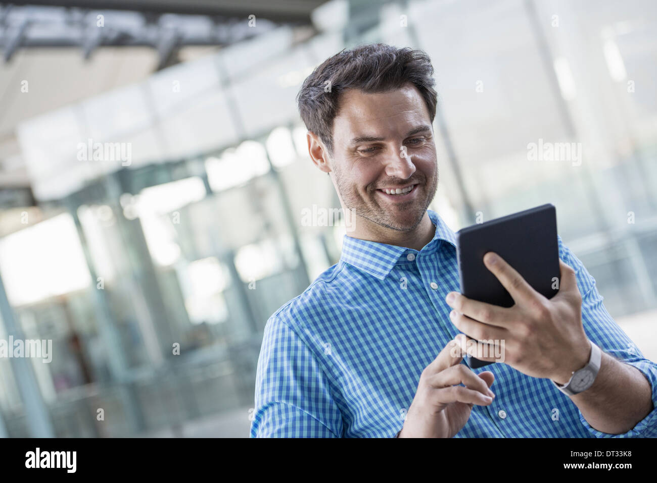 Un homme en chemise bleue à l'aide d'une tablette numérique Banque D'Images