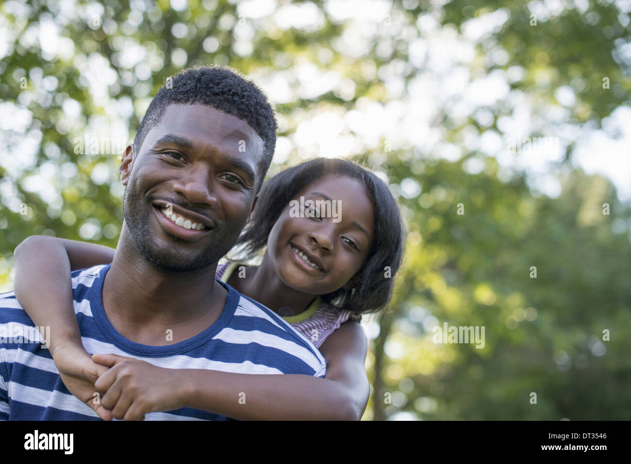Un homme donnant à un enfant un à l'ombre des arbres un jour d'été Banque D'Images