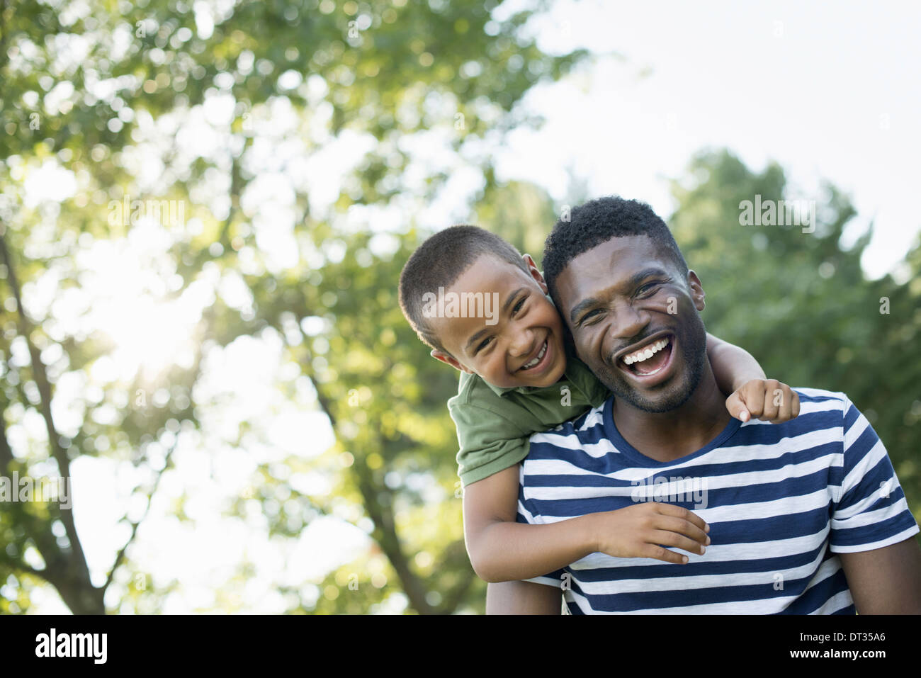 Un homme donnant à un enfant un à l'ombre des arbres un jour d'été Banque D'Images