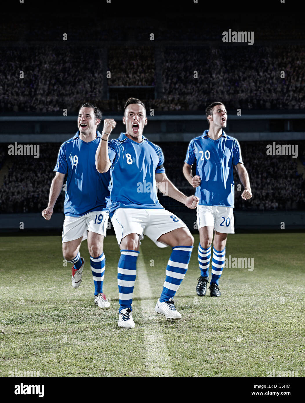 Joueurs de football cheering on field Banque D'Images