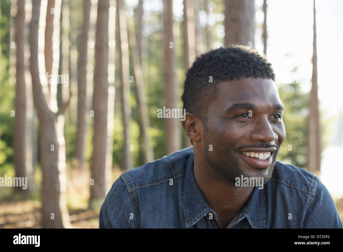 Un homme en chemise bleue dans l'ombre des arbres Banque D'Images