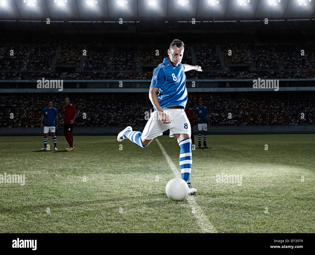Soccer player kicking ball on field Banque D'Images