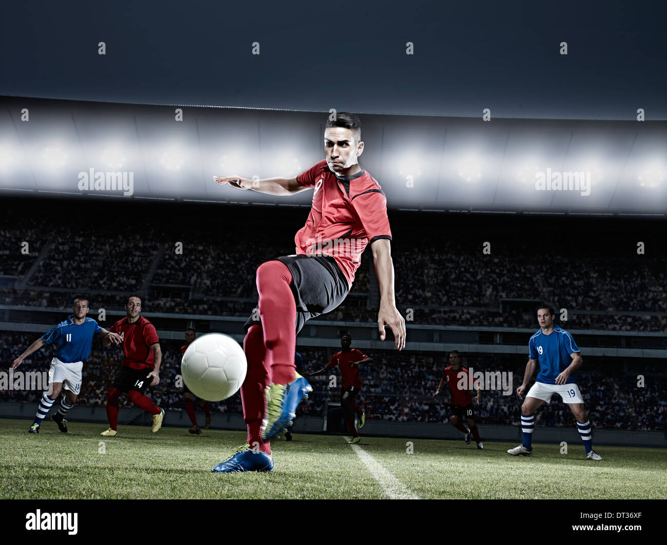 Soccer player kicking ball on field Banque D'Images